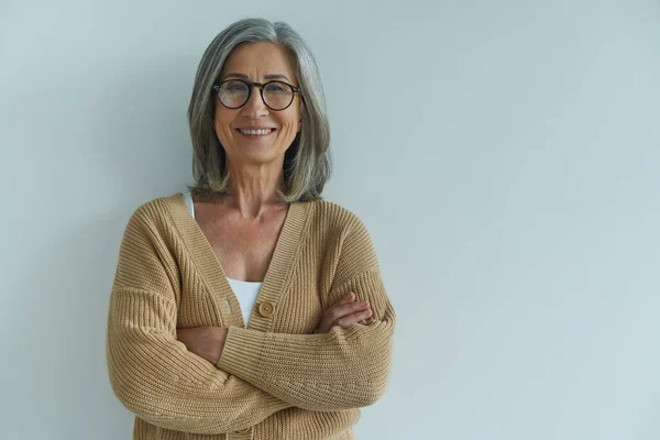 Mulher Sênior Elegante Mantendo Braços Cruzados Sorrindo Enquanto Está Contra — Fotografia de Stock