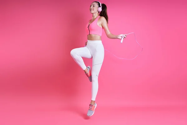 Happy Young Woman Sports Clothing Jumping Rope Pink Background — Stockfoto