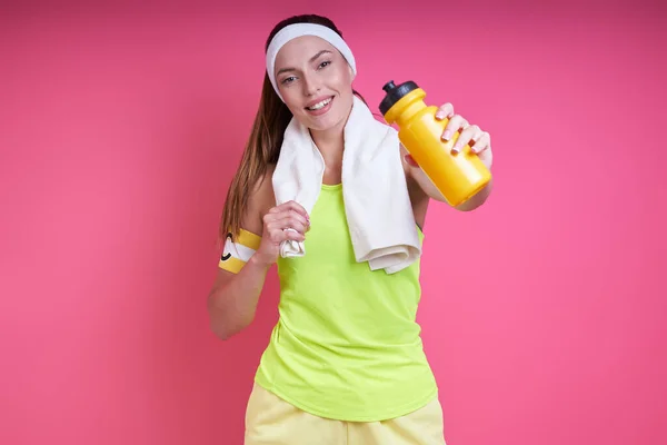 Happy Woman Sports Clothing Stretching Out Hand Bottle Pink Background — Fotografia de Stock