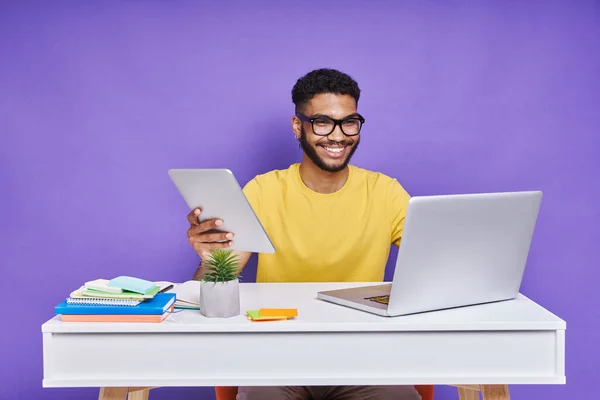 Confident African Man Using Technologies While Sitting Desk Purple Background — Stockfoto