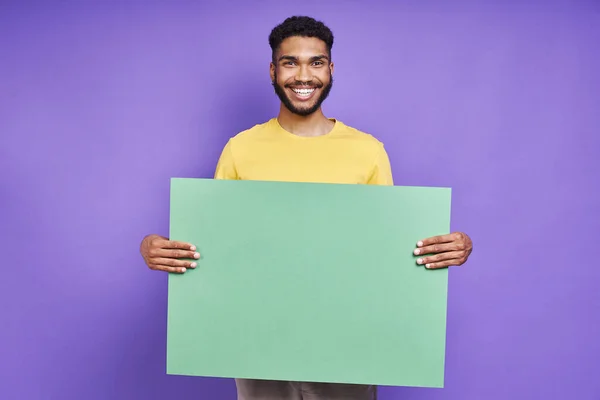 Happy African Man Holding Green Banner While Standing Purple Background — Zdjęcie stockowe