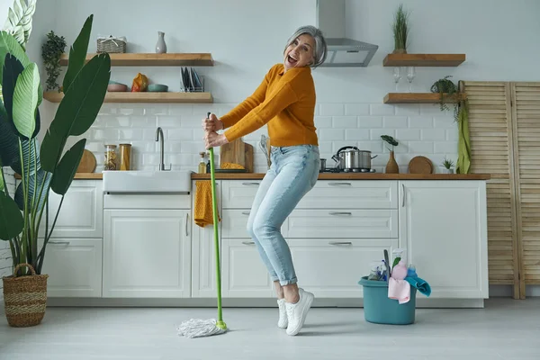 Playful Senior Woman Dancing Mop While Standing Domestic Kitchen — Stockfoto