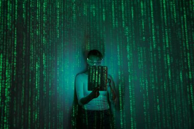 Woman in futuristic glasses using digital tablet against dark background with green symbols