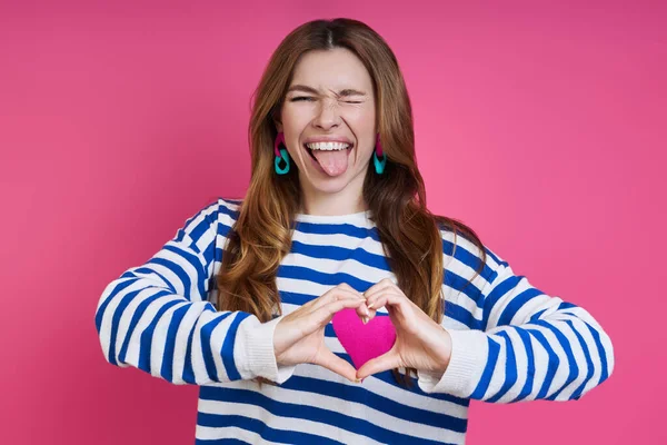 Playful Young Woman Gesturing Heart Shape While Standing Colored Background — Fotografia de Stock