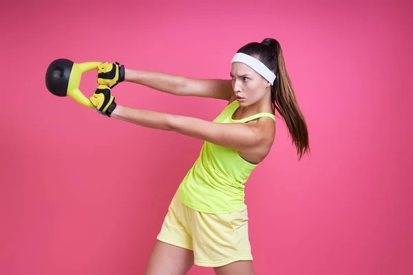 Skoncentrowana Młoda Kobieta Ćwiczy Kettlebell Różowym Tle — Zdjęcie stockowe