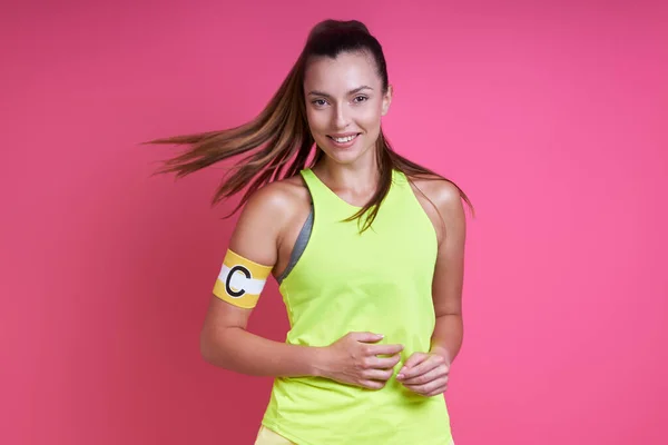 Happy Young Woman Sports Clothing Wearing Captain Band Pink Background — ストック写真