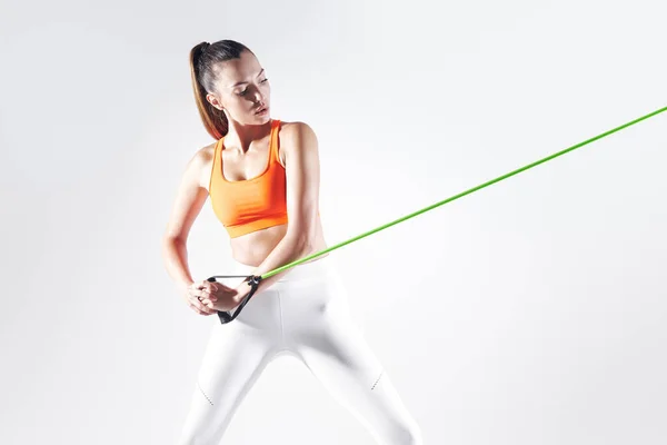Concentrated Woman Using Resistance Band While Exercising White Background — Zdjęcie stockowe