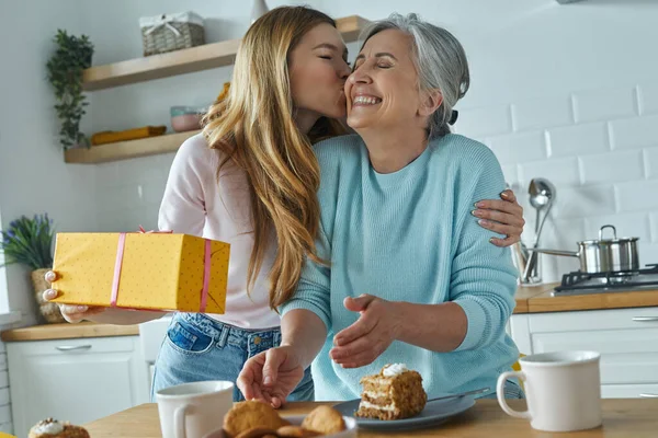 Young Woman Kissing Her Mother Holding Gift Box While Spending — Φωτογραφία Αρχείου