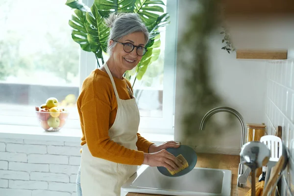 Cheerful Senior Woman Washing Dishes Domestic Kitchen — стоковое фото