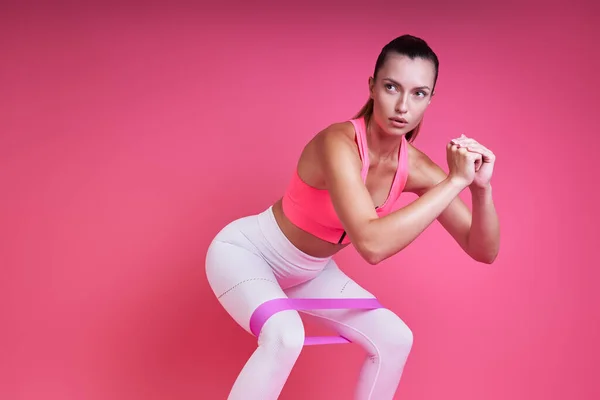 Sebevědomá Mladá Žena Cvičení Elastickou Páskou Proti Růžové Pozadí — Stock fotografie