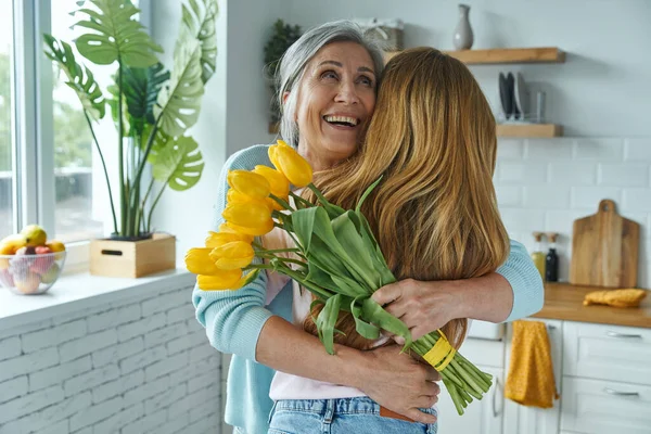 Happy Senior Woman Embracing Her Daughter Holding Bunch Yellow Tulips — Stock Photo, Image