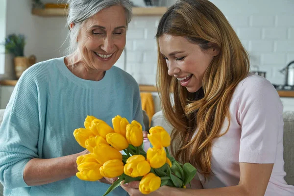 Happy Senior Mother Receiving Bunch Tulips Her Daughter While Sitting — Φωτογραφία Αρχείου