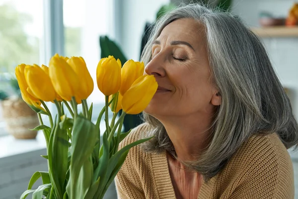 Happy Senior Woman Smelling Bunch Yellow Tulips While Relaxing Home — Stockfoto