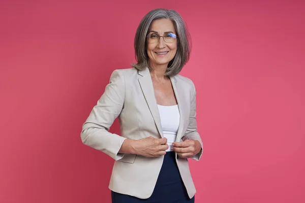 Confident Senior Woman Buttoning Her Jacket While Standing Pink Background — Photo