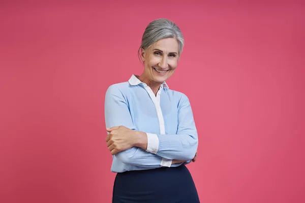 Confident Senior Woman Keeping Arms Crossed While Standing Pink Background — 图库照片
