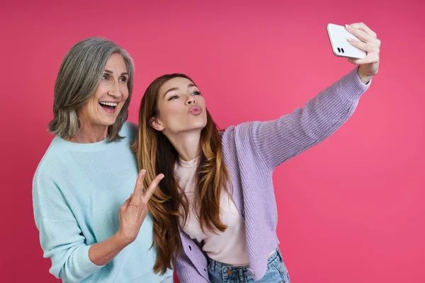 Playful Senior Mother Adult Daughter Making Selfie Pink Background — Φωτογραφία Αρχείου