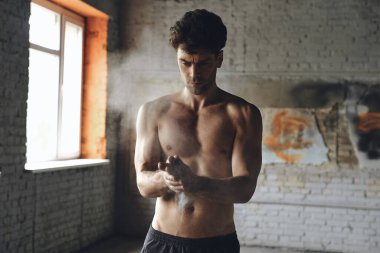 Confident young man preparing hands with talcum powder before training