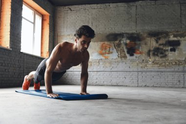 Confident young man doing push-up exercises in gym