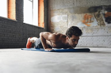 Confident young man doing push-up exercises in gym
