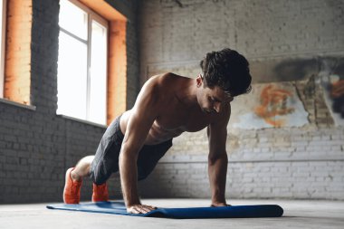 Concentrated young man doing push-up exercises in gym