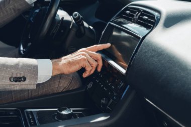 Close-up of man using control panel while sitting on the front seat of a car