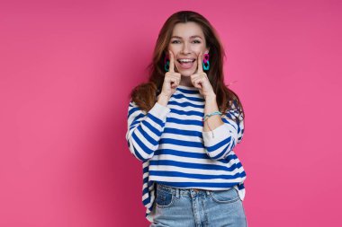 Renkli arka planda dururken gülümseyen güzel bir genç kadın.