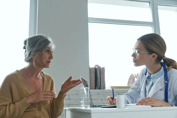 Senior Woman Telling Her Problems While Visiting Doctor Clinic — Zdjęcie stockowe