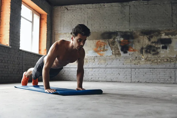 Confident young man doing push-up exercises in gym