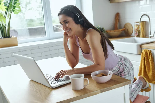 Beautiful Woman Headphones Using Laptop While Sitting Kitchen Island Home — Stockfoto