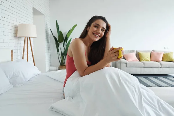 Happy Young Woman Holding Coffee Cup While Sitting Bed Home — Fotografia de Stock
