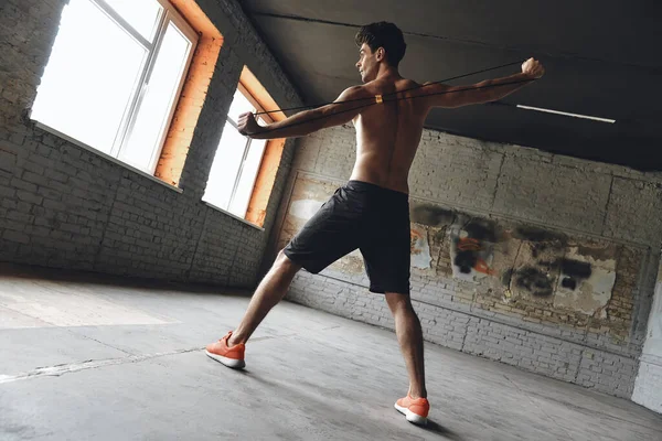 Full Length Concentrated Young Man Exercising Resistance Band Gym — Stok fotoğraf