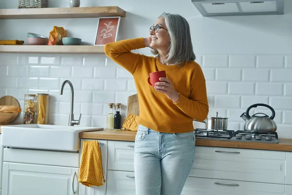 Dreamful Senior Woman Holding Cup Smiling While Standing Domestic Kitchen — Foto de Stock