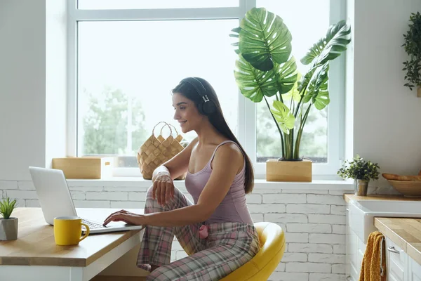 Beautiful Woman Headphones Using Laptop While Sitting Kitchen Counter Home — Stockfoto