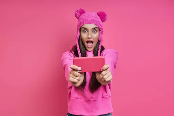Shocked Young Woman Funky Hat Looking Her Smart Phone Pink — 스톡 사진