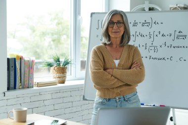 Senior woman standing near the whiteboard at classroom