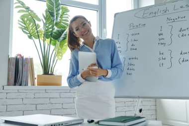 Beautiful young woman standing near the whiteboard at the classroom