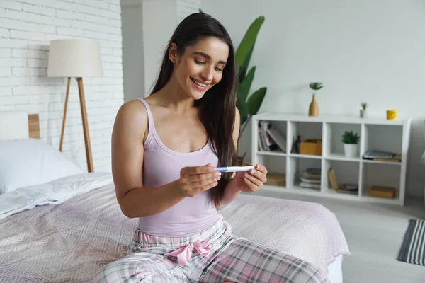 Happy Young Woman Looking Pregnancy Test While Sitting Bed Home — Stock Fotó