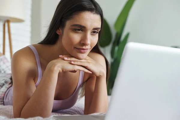 Thoughtful Young Woman Using Laptop While Lying Bed Home — Stock Photo, Image