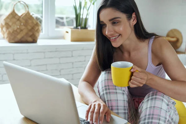 Happy Young Woman Enjoying Morning Coffee Using Laptop Domestic Kitchen — Φωτογραφία Αρχείου