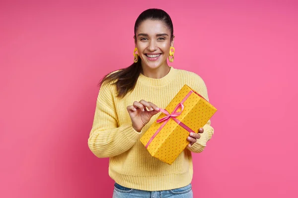 Happy Young Woman Opening Gift Box While Standing Colored Background — Foto de Stock