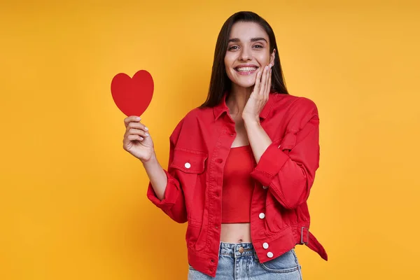 Happy Young Woman Holding Paper Heart While Standing Yellow Background — Fotografia de Stock