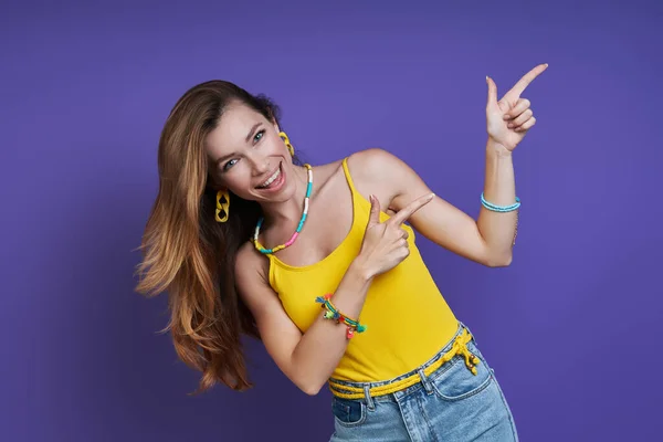 Happy Young Woman Pointing Away While Standing Purple Background — Stock Photo, Image