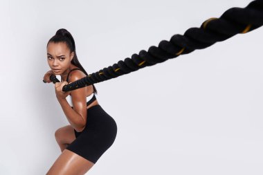 Concentrated African woman pulling a rope against white background