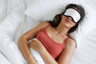 Top view of beautiful woman wearing sleeping mask while lying in bed