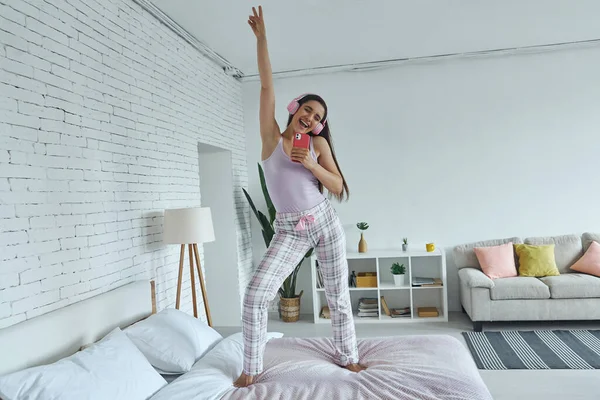 Playful Woman Headphones Using Smart Phone Microphone While Dancing Bed — Stock Fotó