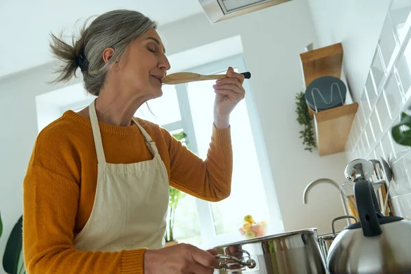 Confident Senior Woman Tasting Her Meal While Cooking Domestic Kitchen — Fotografia de Stock