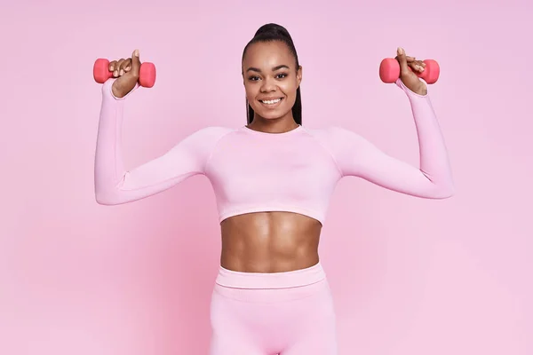 Happy Young African Woman Exercising Dumbbells While Standing Pink Background — Photo