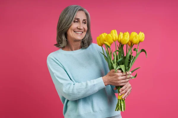 Happy Senior Woman Looking Bunch Tulips While Standing Pink Background — Photo