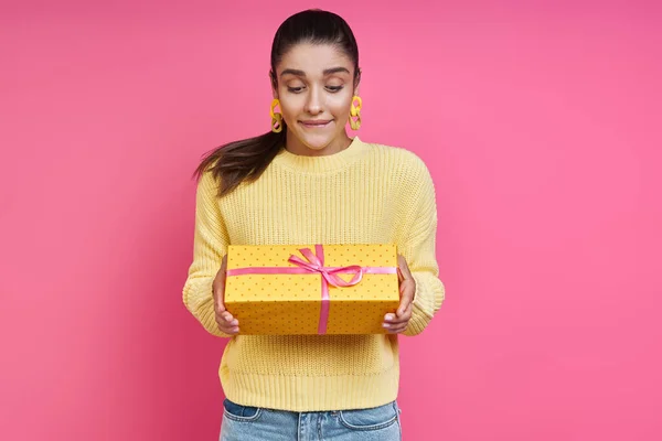 Curious Young Woman Looking Gift Box While Standing Colored Background — Stok fotoğraf