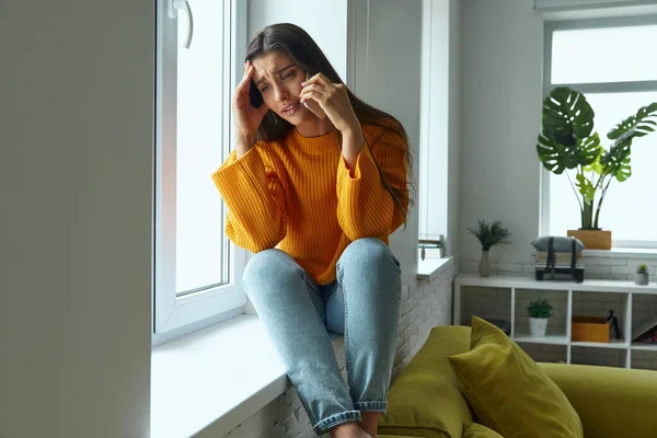 Depressed Woman Talking Mobile Phone Touching Head While Sitting Window — Stok fotoğraf